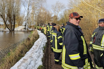 Feuerwehrkamerad:innen am Deich mit Sandsäcken